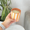 Bougie artisanale rayée orange clair en terre cuite parfum Ambre